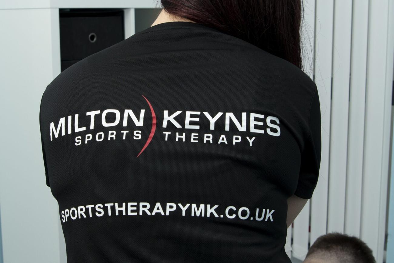 A Milton Keynes Sports Therapy therapist in the branded club shirt.